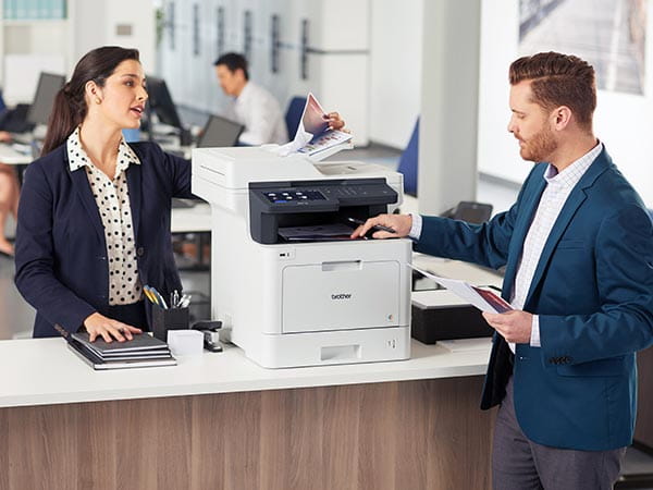 Man and woman using shared printer in corporate office