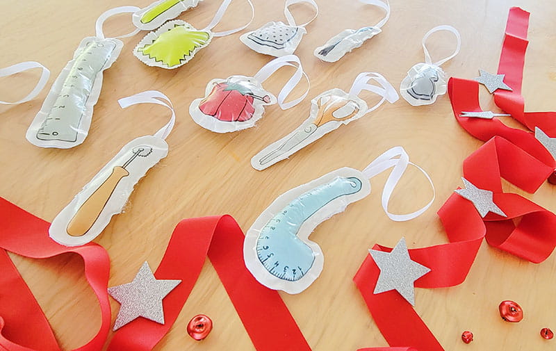 DIY plush ornaments all standing on desk with red ribbon on the side and some silver stars